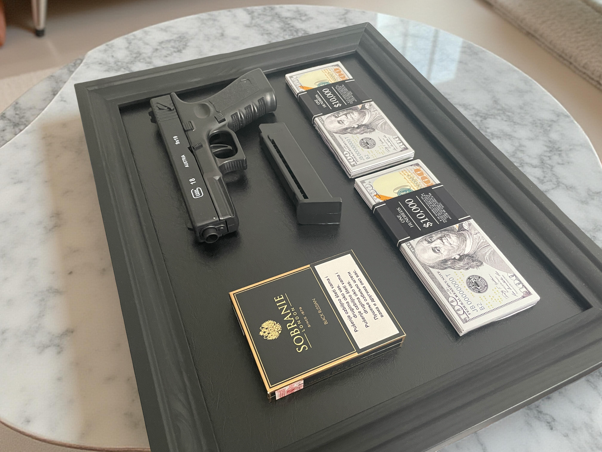 Glock gun with magazine, money, and Sobrane cigarettes on a black wooden frame.