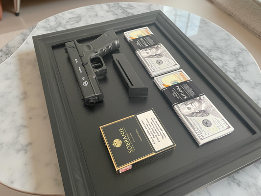 Glock gun with magazine, money, and Sobrane cigarettes on a black wooden frame.