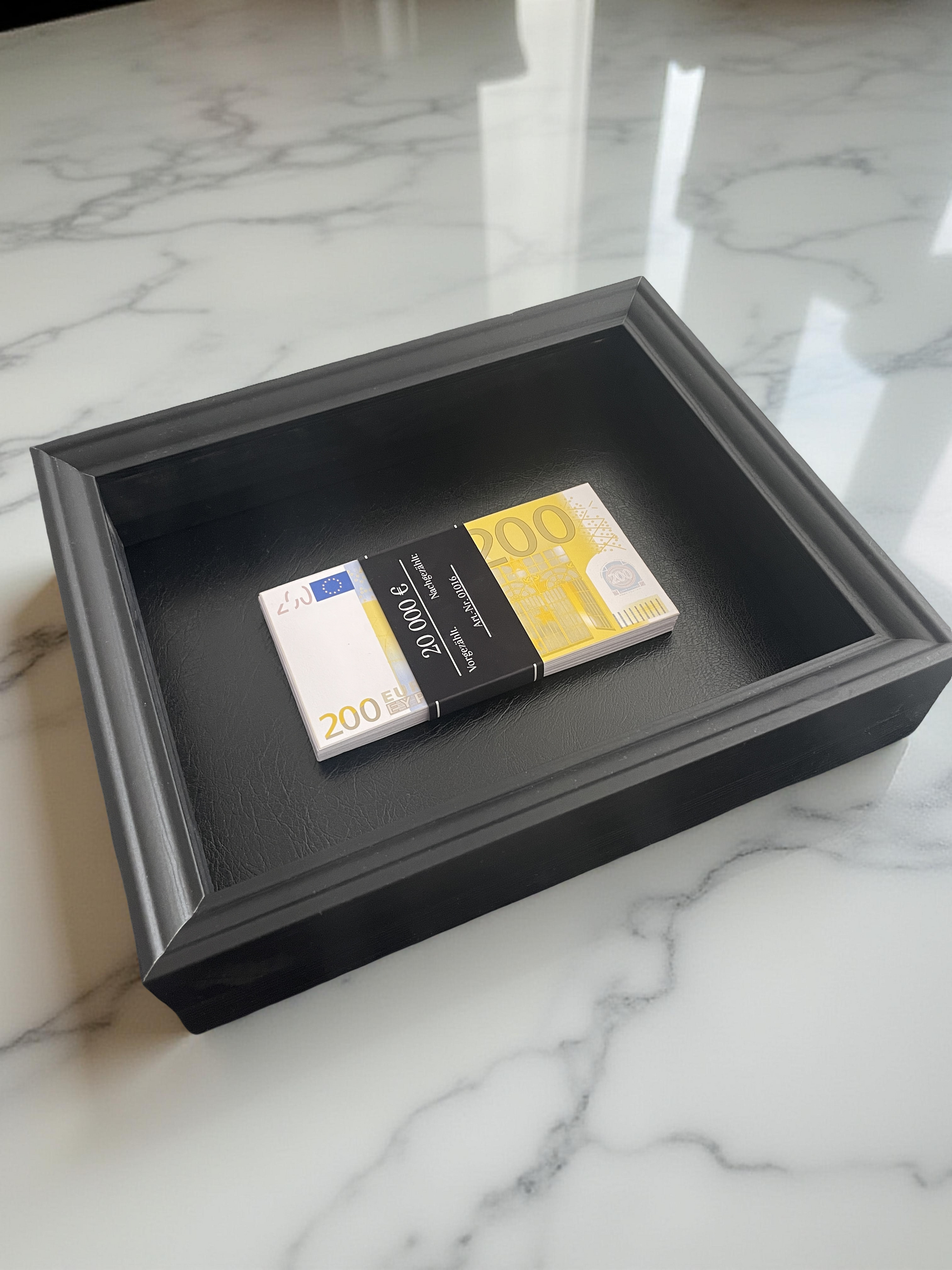 Black shadow box with Euro Stack on a marble surface.