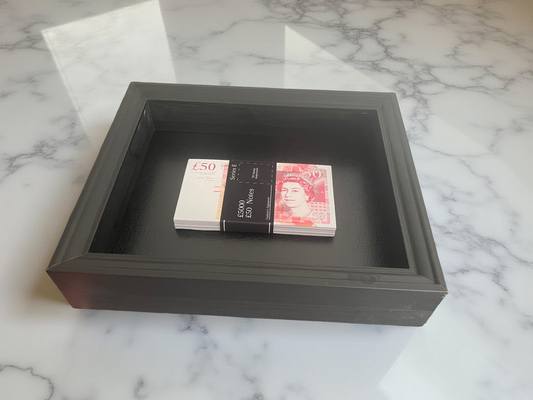Stack of GBP banknotes in a dark wooden box on a marble surface