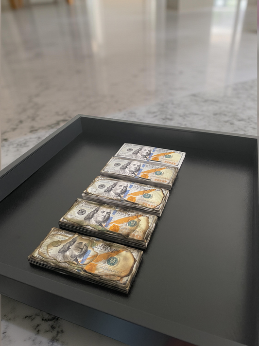 Stacks of U.S. dollar bills on a dark tray with a blurred background
