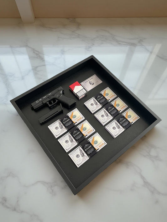A black shadowbox showcasing a Glock, Marlboro cigarettes, an Amex card, and six stacks of USD.